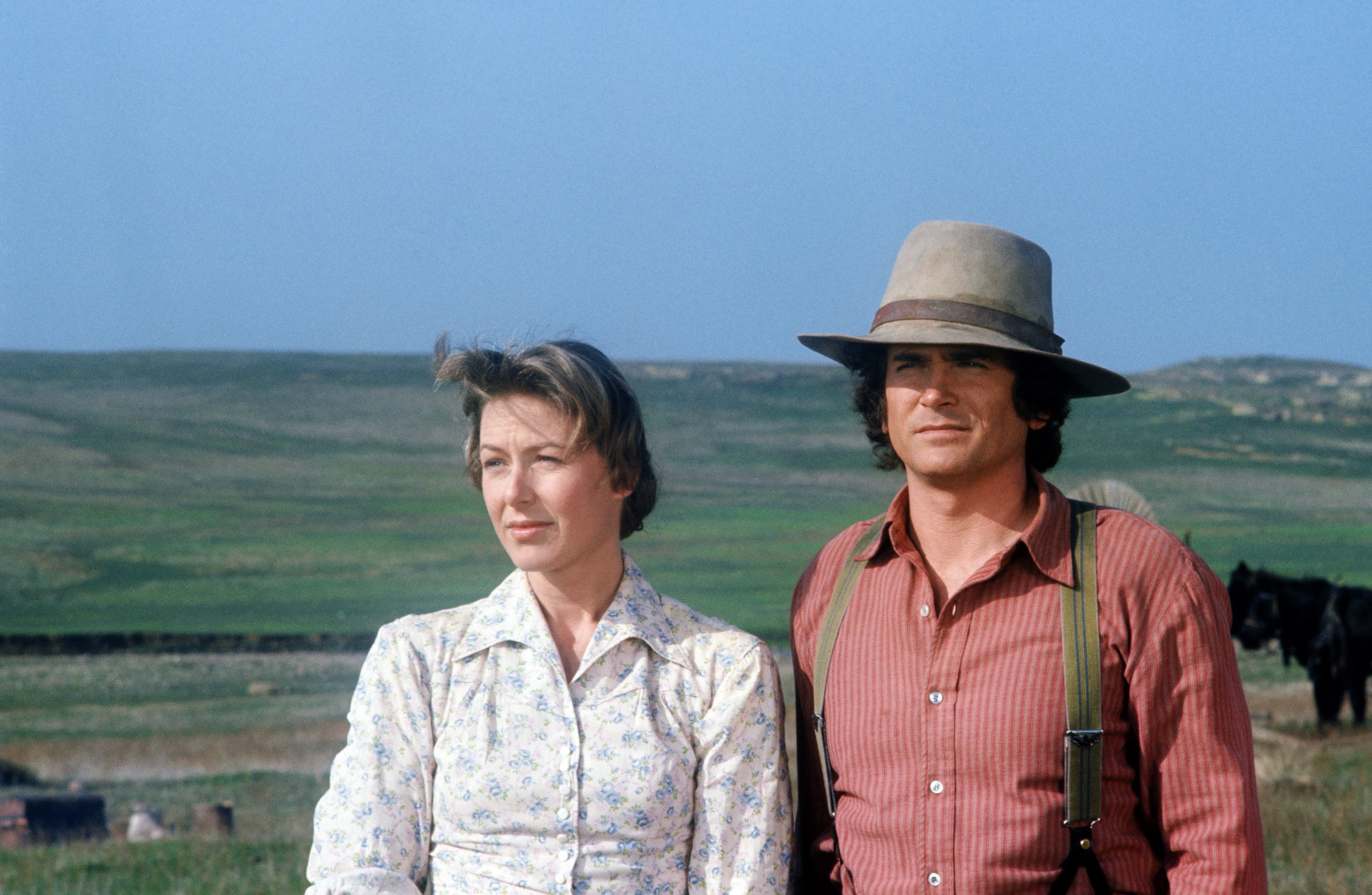 Karen Grassle and Michael Landon standing in a field filming 'Little House on the Prairie.'
