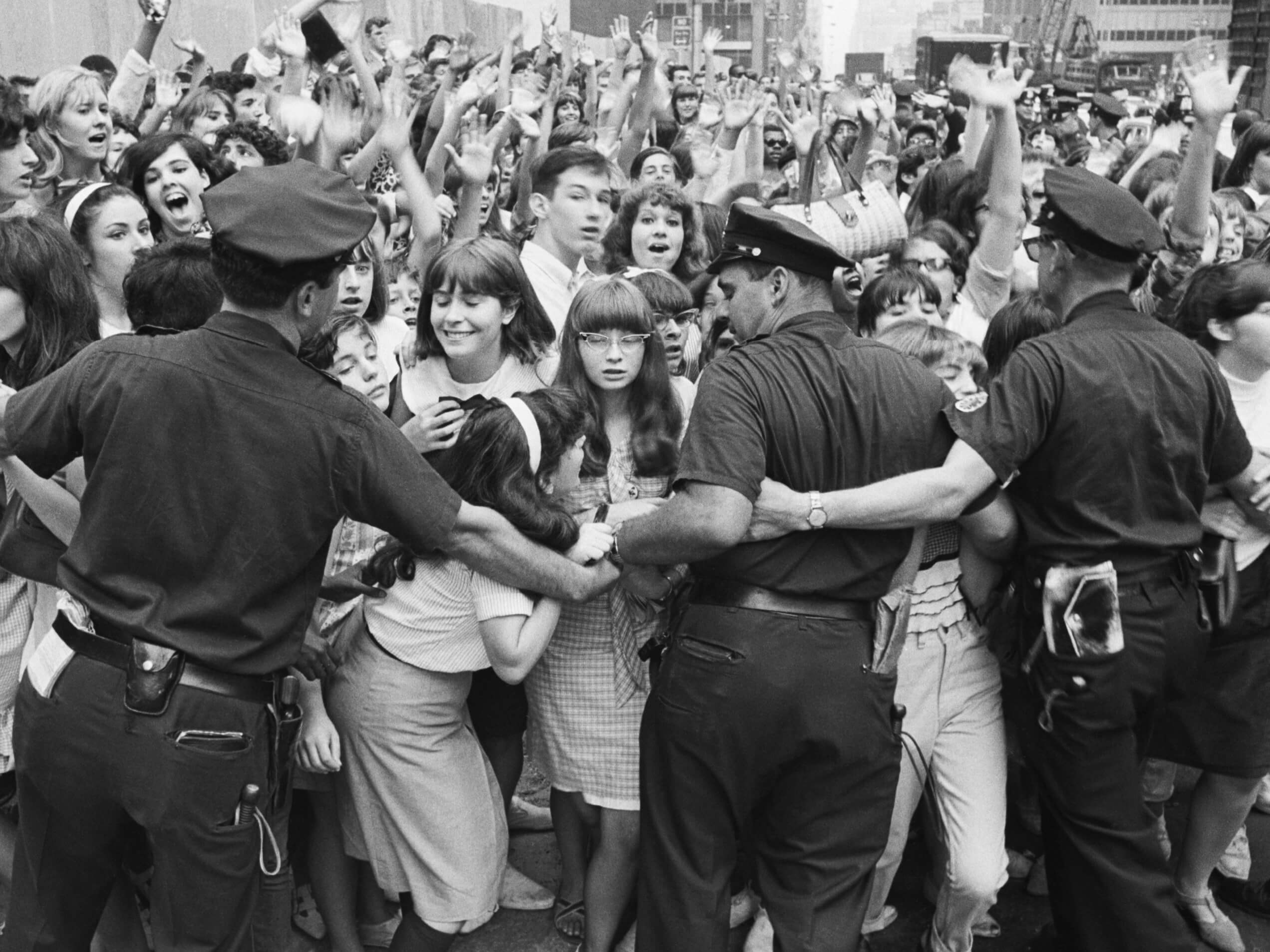 A black-and-white photo of police with Beatles fans