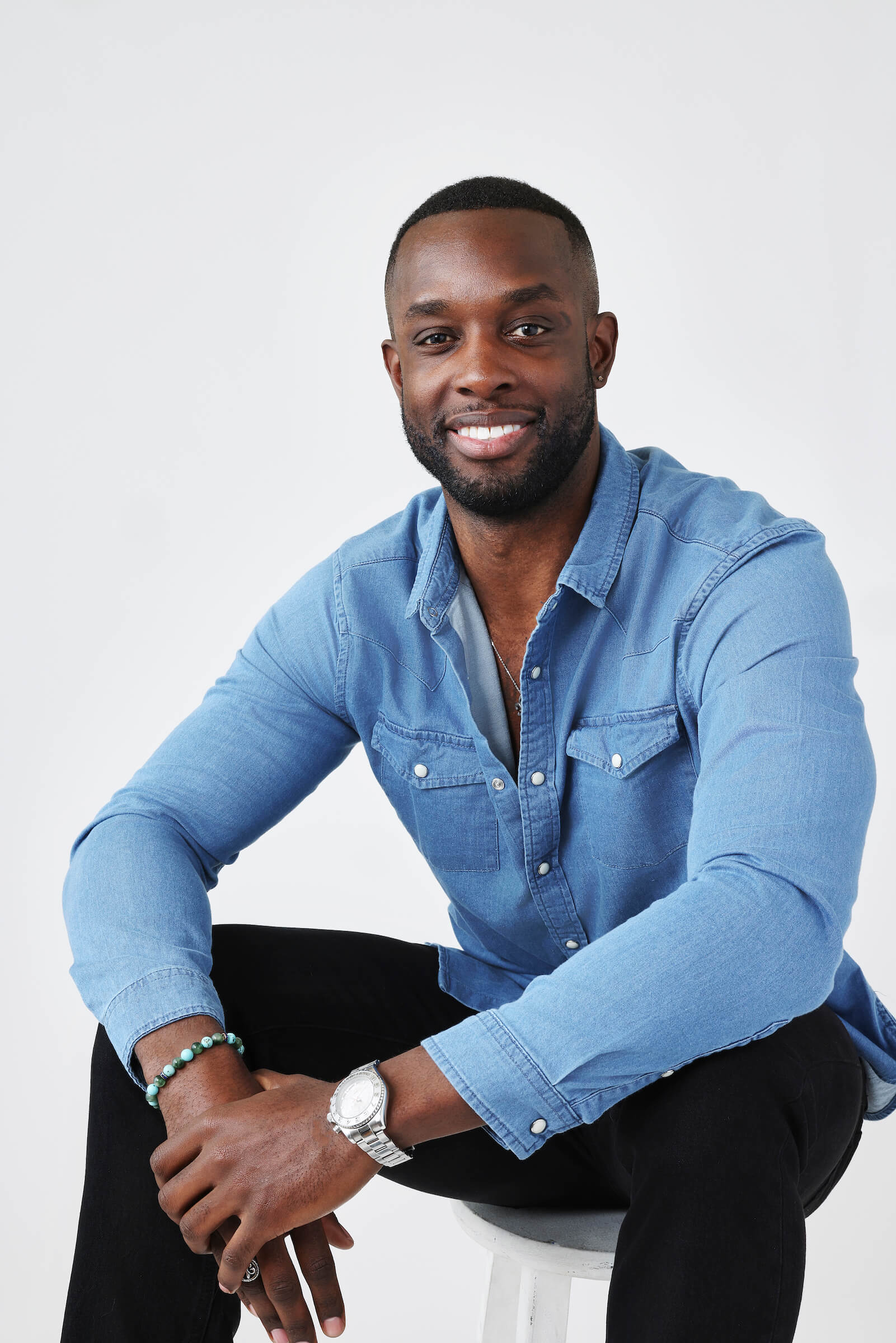 Aaron Bryant from 'The Bachelorette' 2023 sitting in a chair wearing a blue shirt and smiling