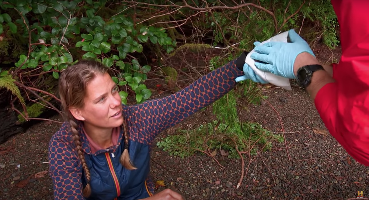 'Alone' Season 2 cast member Mary Kate holding her injured hand for a crew member to examine