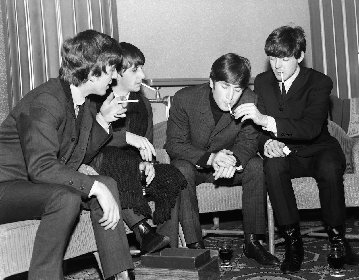 Beatles members (from left) George Harrison, Ringo Starr, John Lennon, and Paul McCartney sitting and smoking cigarettes backstage in 1963.