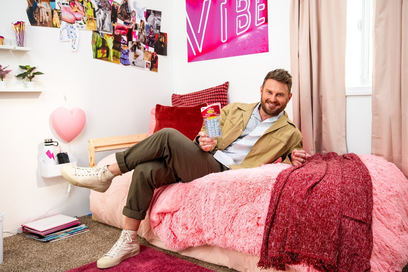 Bobby Berk sits in a pink dorm room 