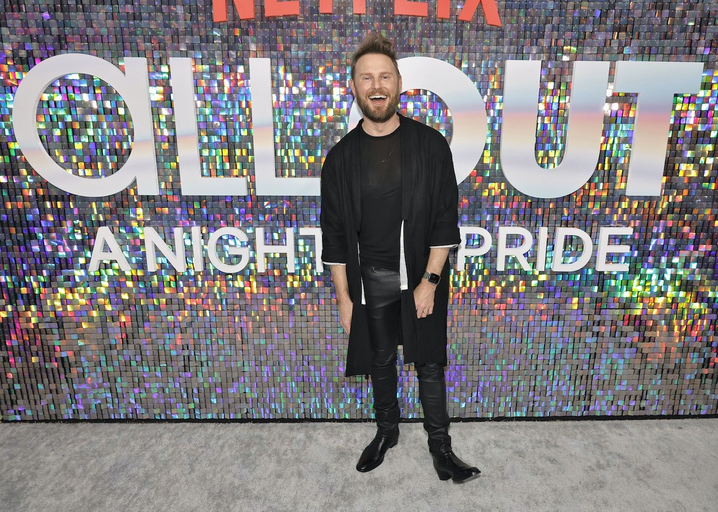 Bobby Berk smiles in front of a sparkling wall