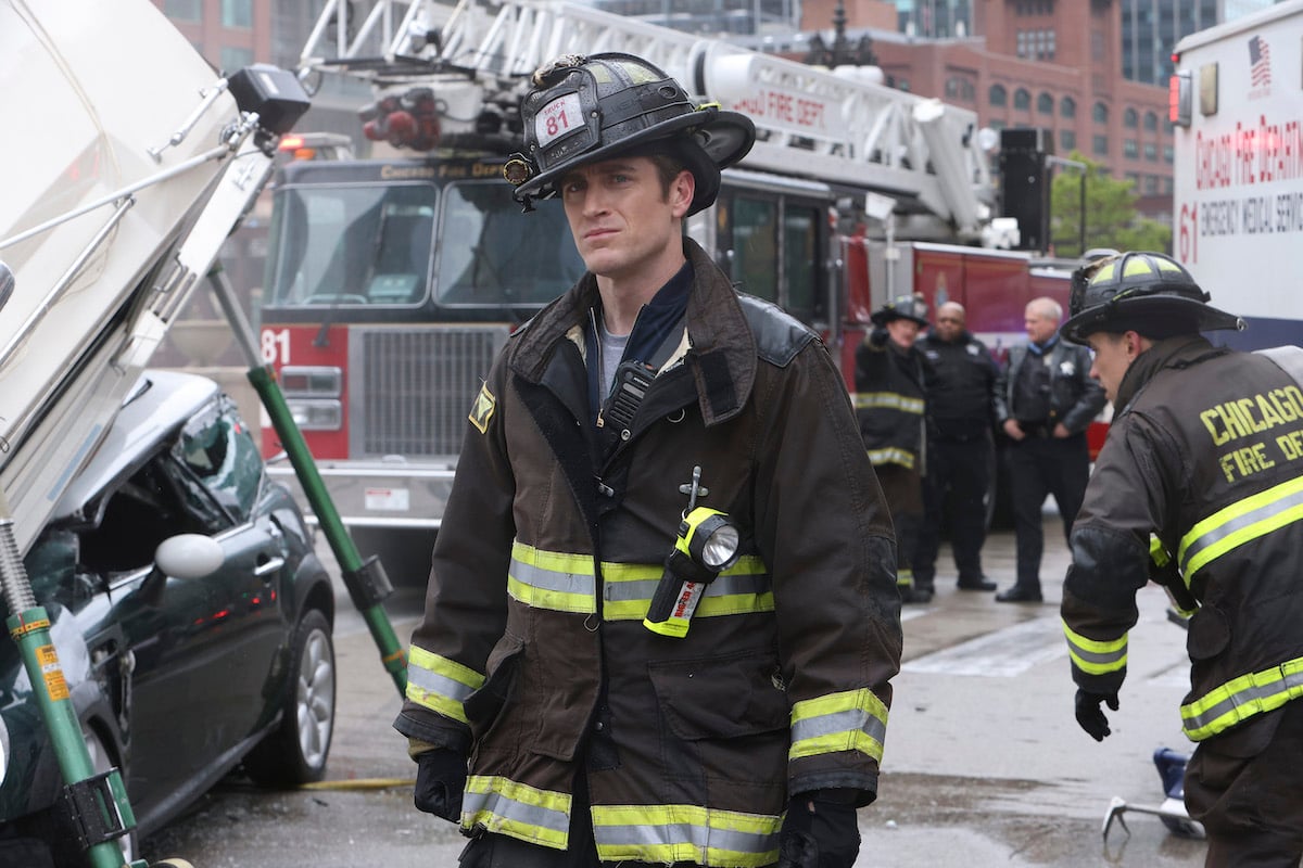 Confused looking firefighter standing in front of a fire truck in 'Chicago Fire' Season 11