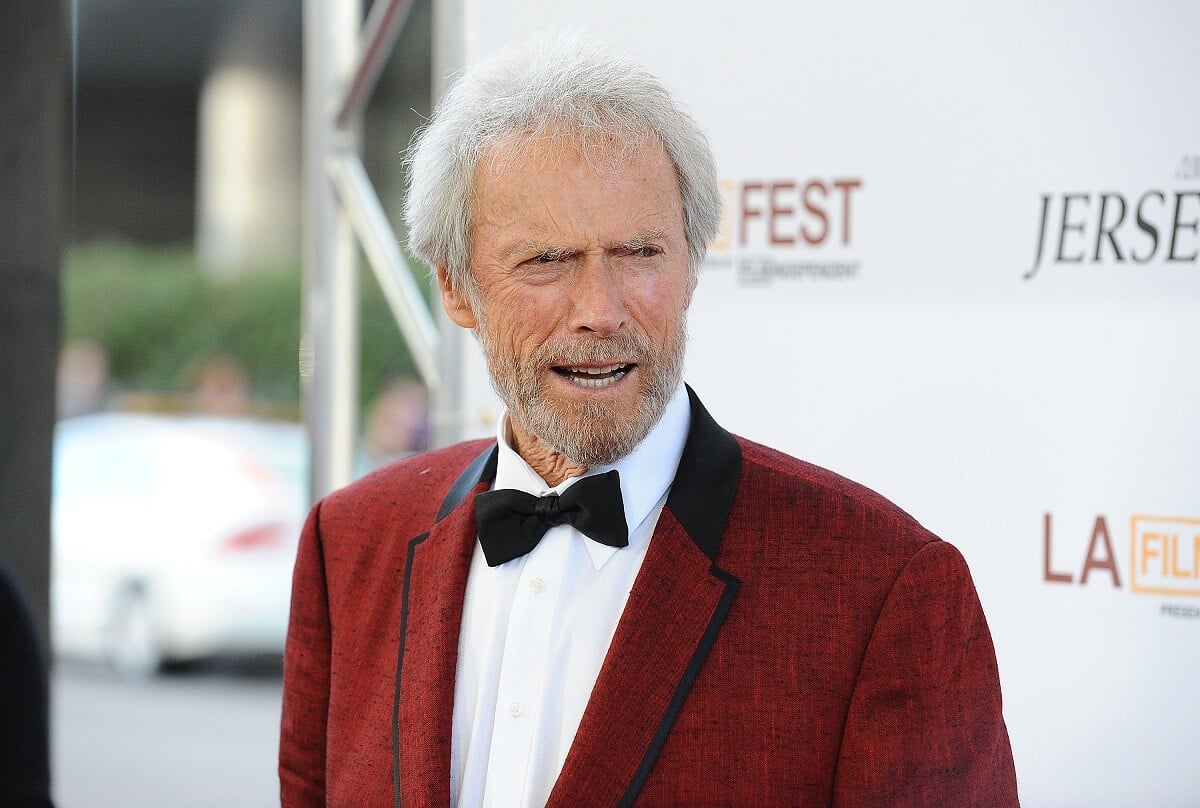 Clint Eastwood talking in a red suit while taking a picture at the Los Angeles Film Festival .