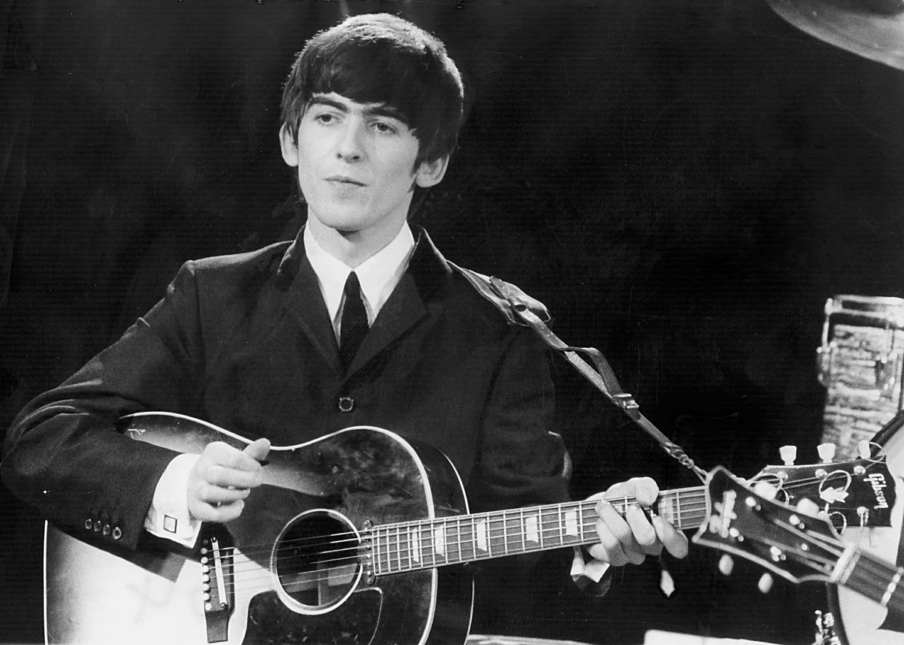 George Harrison performs at a concert with The Beatles