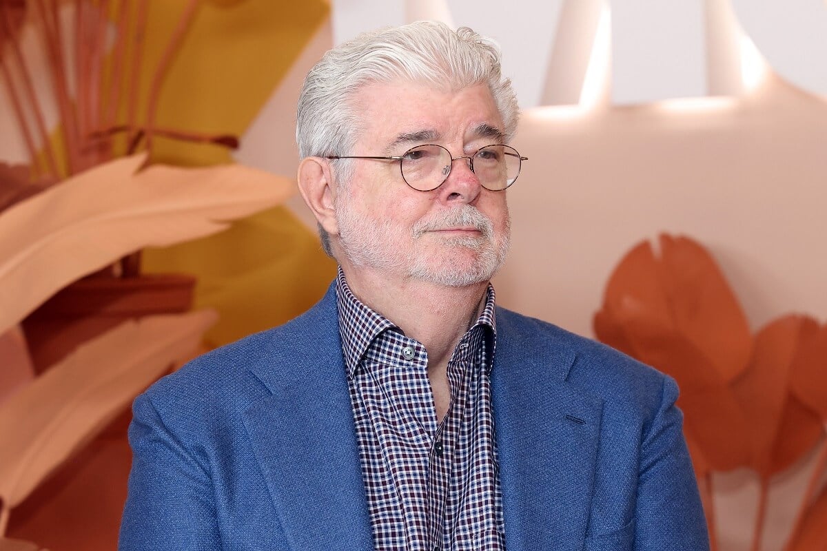 George Lucas taking a picture in a blue suit at the Museum of Modern Art.