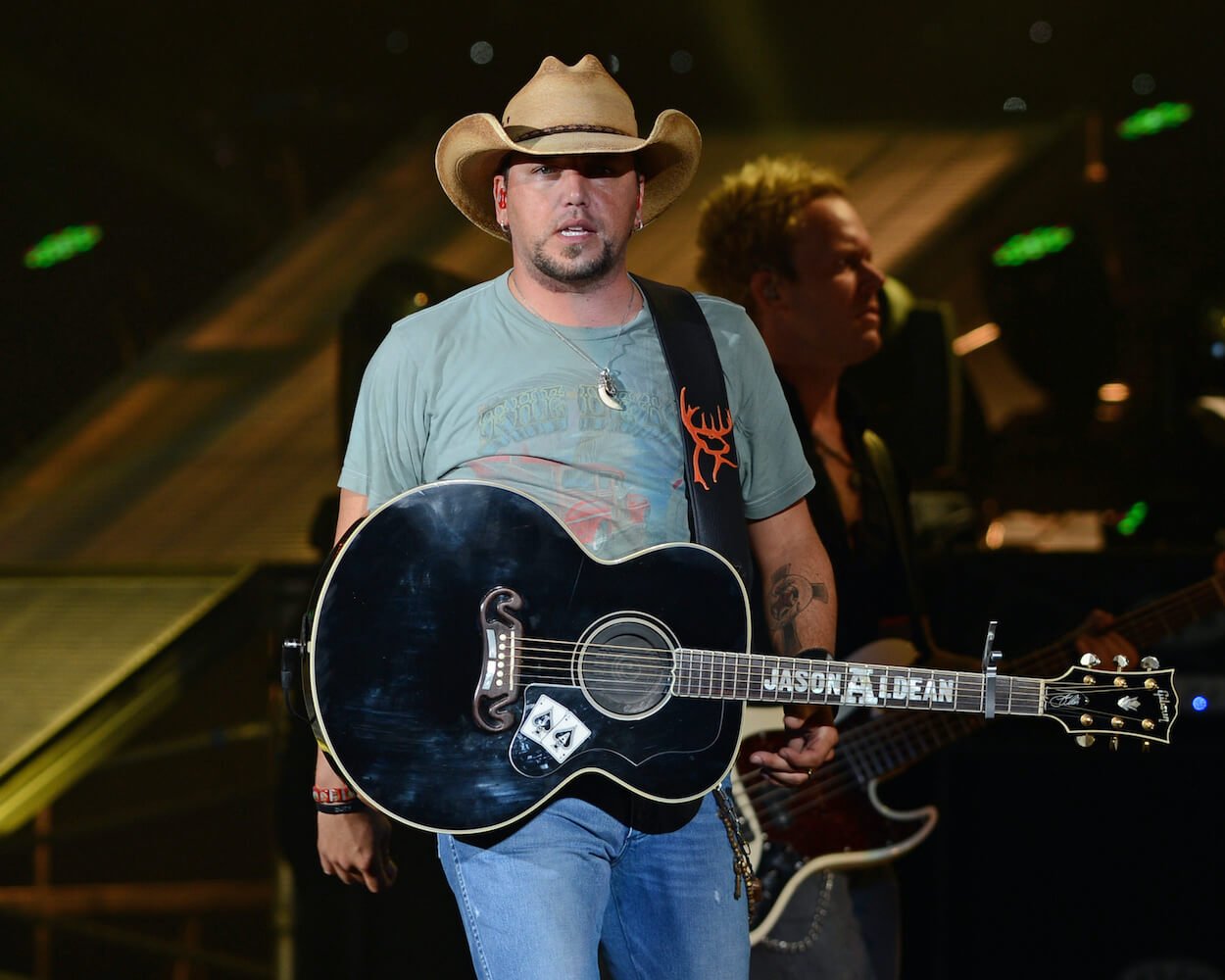 Jason Aldean with an acoustic guitar slung around his neck at a 2012 concert.