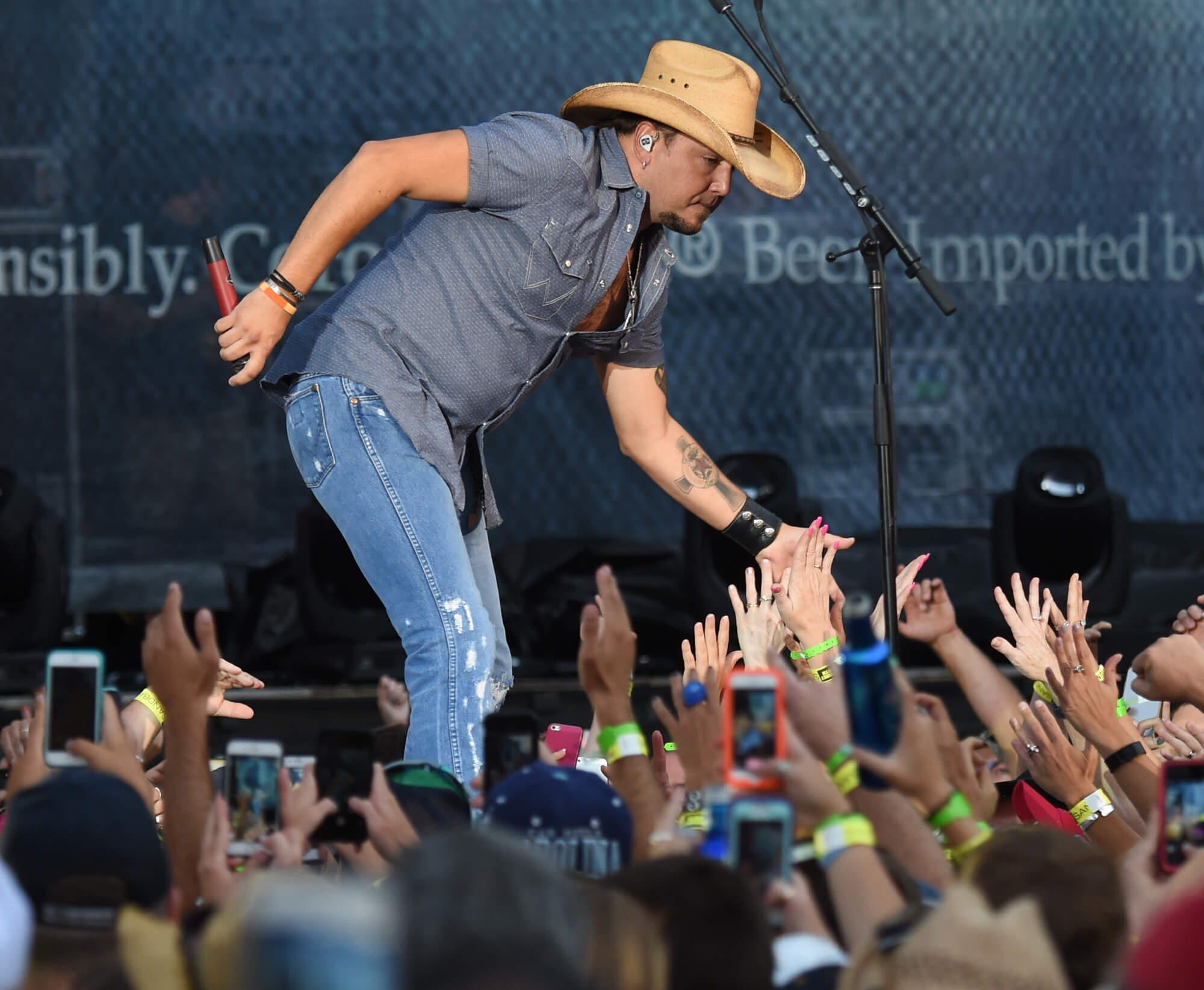 Jason Aldean walking through the concert crowd while putting his hand out