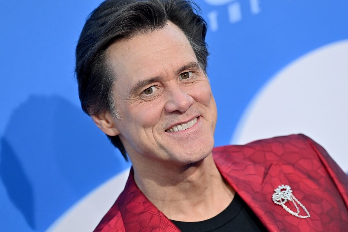 Jim Carrey smiling in a red suit at the premiere of 'Sonic the Hedgehog 2'.