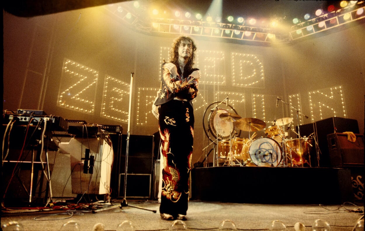 Led Zeppelin guitarist Jimmy Page standing on stage and crossing his arms in front of his chest after a concert.