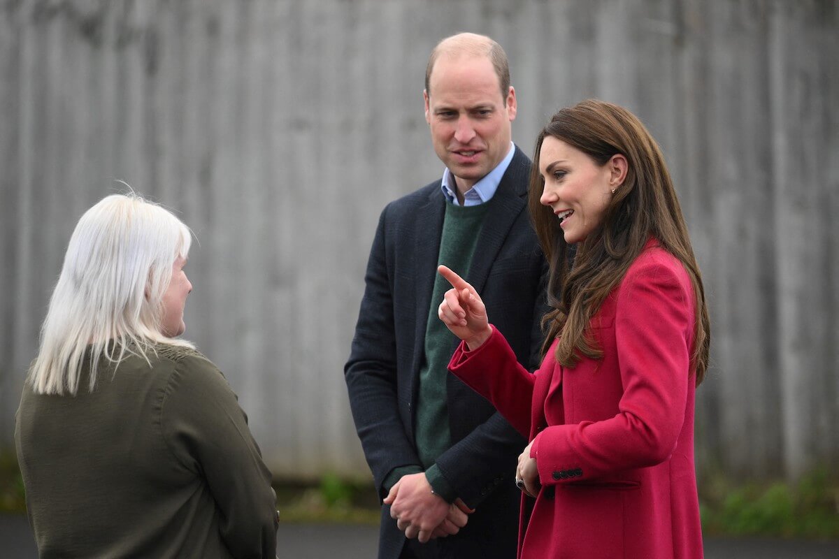 Kate Middleton, whose 'leadership style' includes three body language traits, stands with Prince William and a staff member