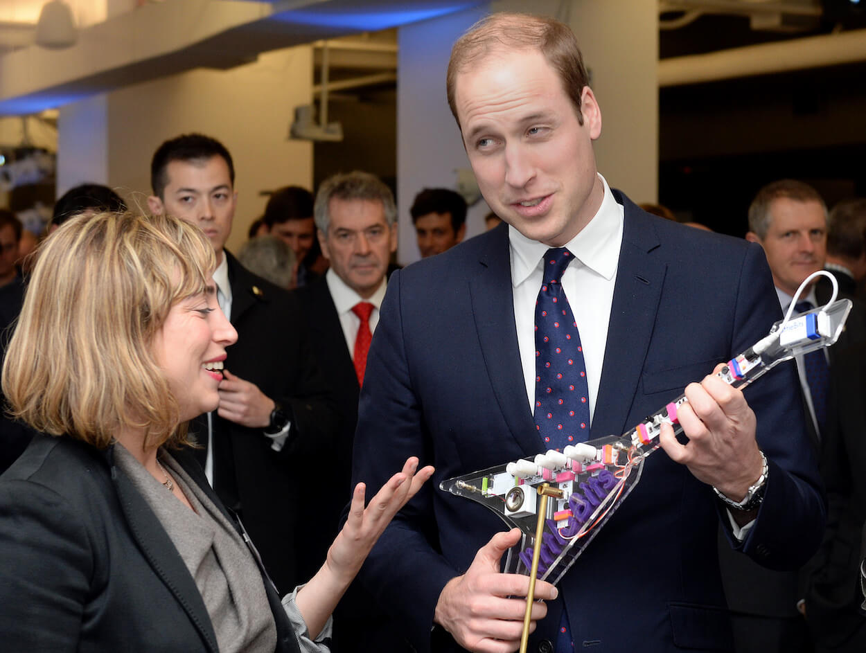 Prince William wearing a suit and tie while playing a Keytar synthesizer in 2014.