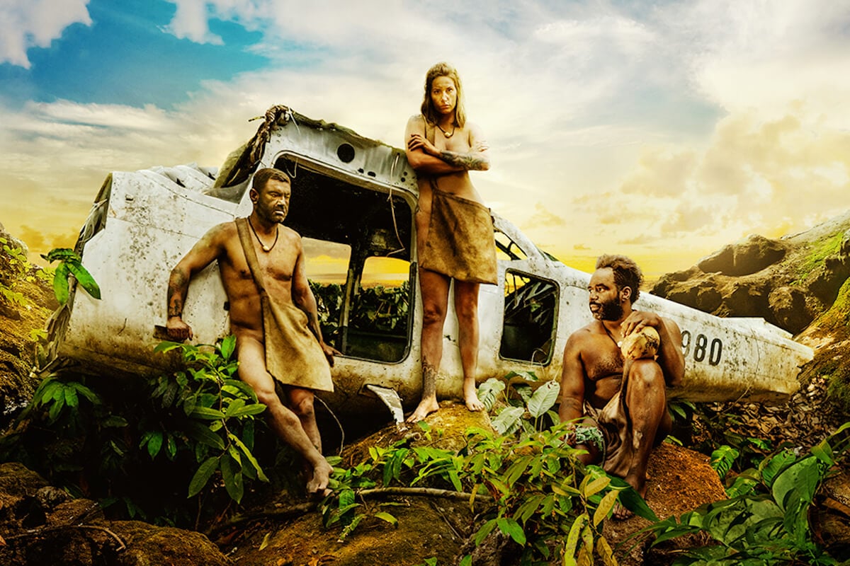 Three 'Naked and Afraid Castaways' cast members posing in front of a crashed plane