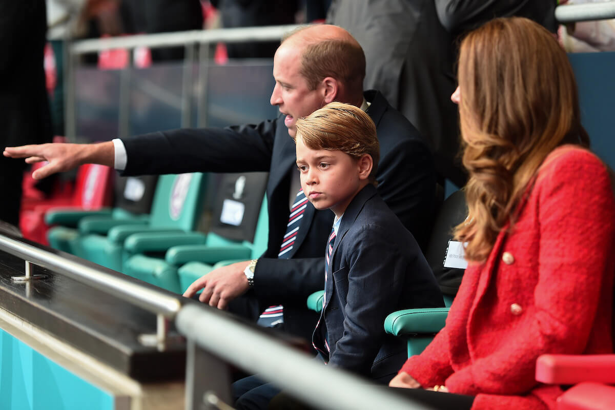 Prince George, whose heir status doesn't make a big difference to Wales 'home life,' sits with Prince William and Kate Middleton