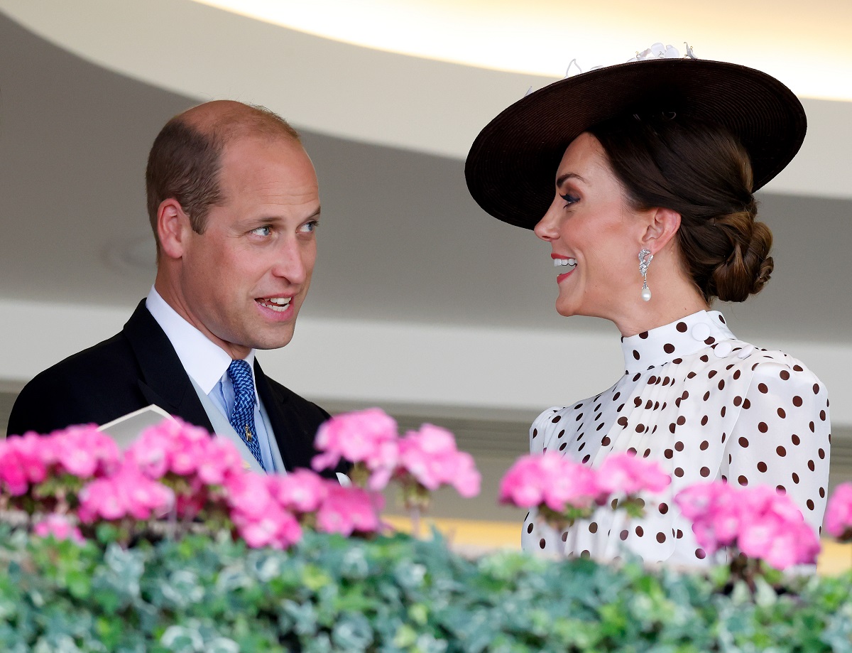 Prince William and Kate Middleton smiling as they speak to each other in the Royal Box during Ascot
