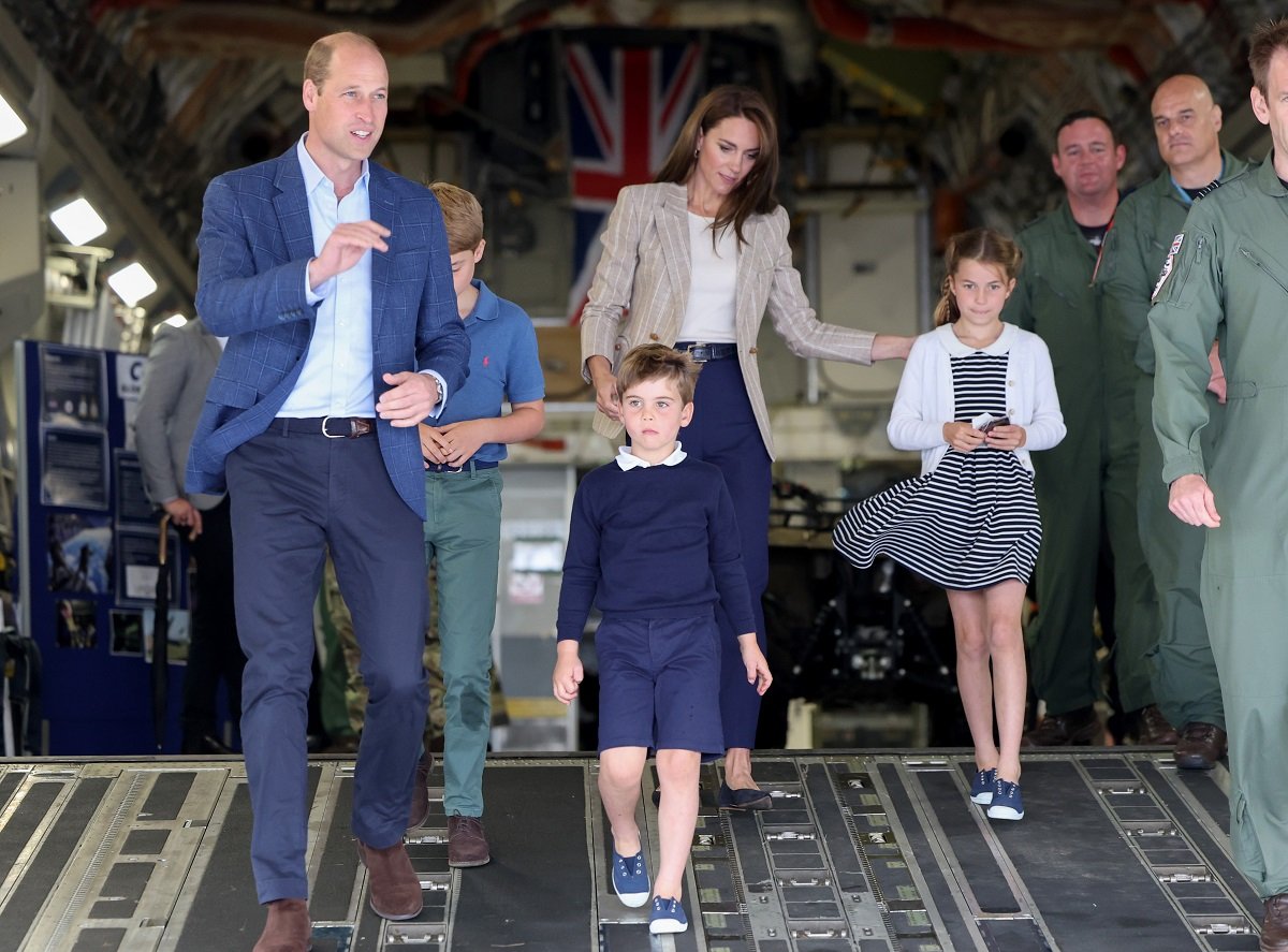 Prince William and Kate Middleton, who a former royal employee says won't force their children to stay at Balmoral in the summer, walk down the ramp of a C17 with their three kids in Fairford, England