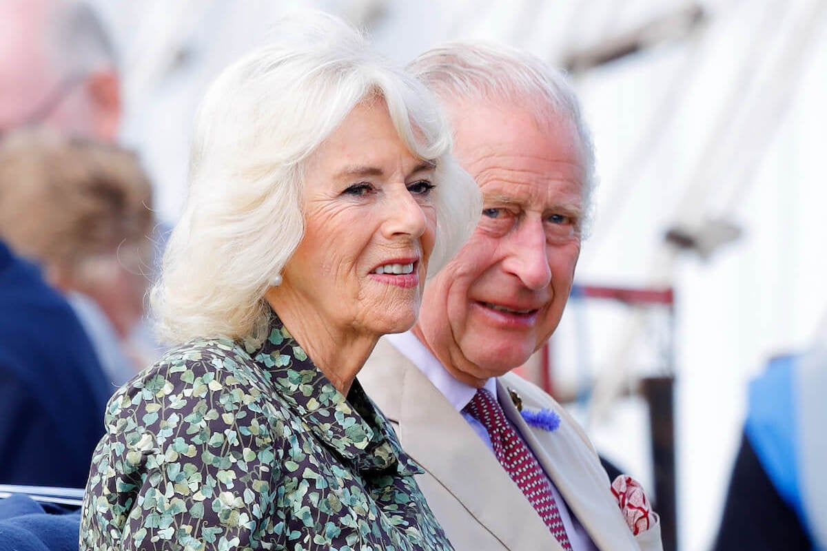 Queen Camilla, whose PDA with King Charles III includes a 'Courtier's Nod,' sits next to King Charles III