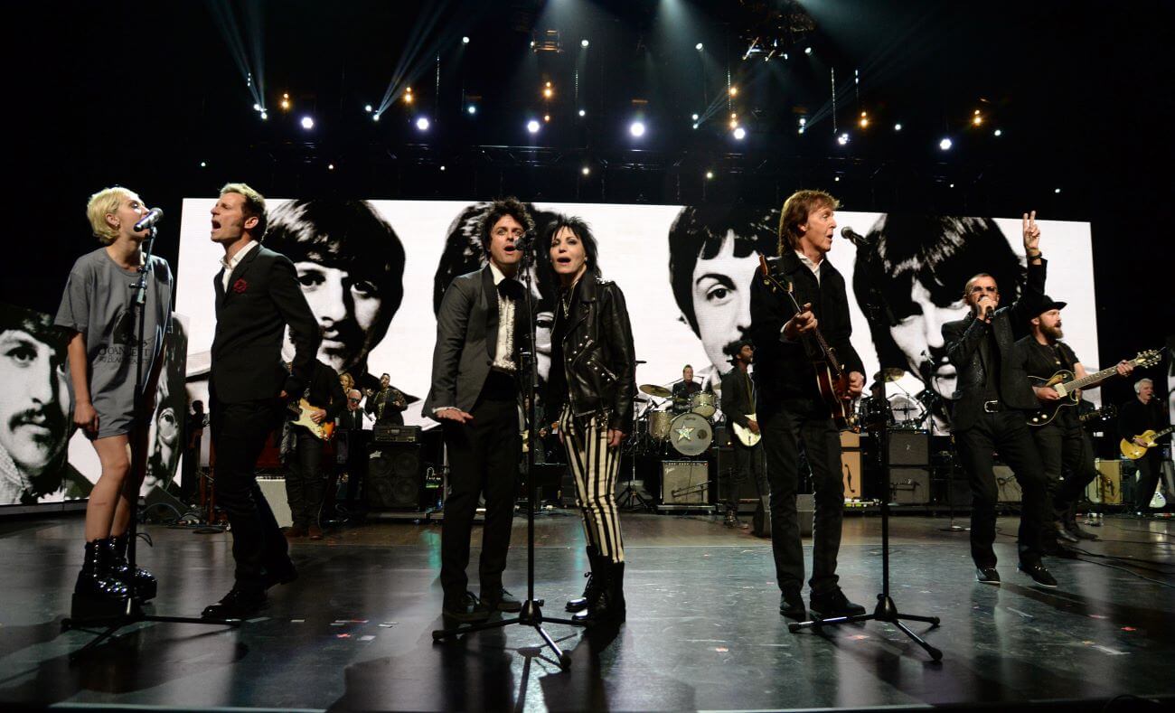 Miley Cyrus, Mike Dirnt, Billie Joe Armstrong, Joan Jett, Paul McCartney, and Ringo Starr singing onstage at the Rock & Roll Hall of Fame ceremony.