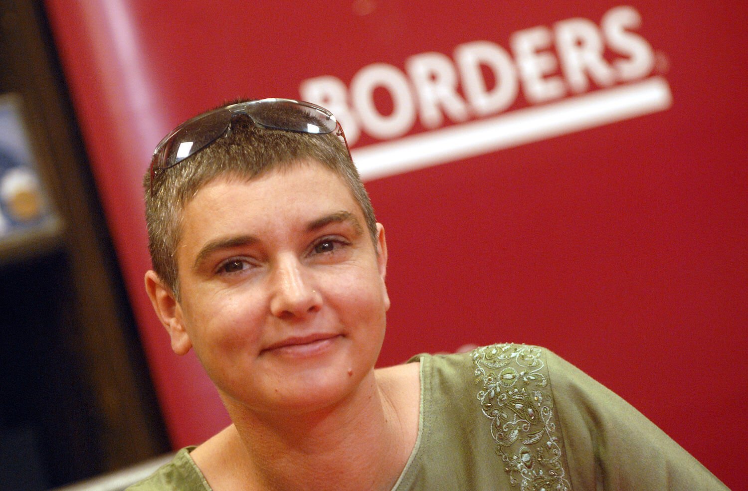 A close-up of Sinead O'Connor against a red 'Borders' background