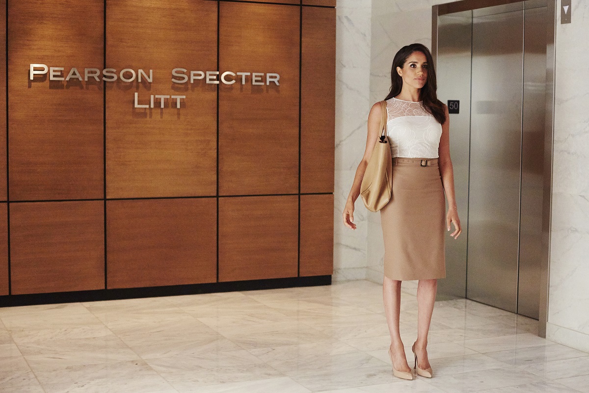 Meghan Markle as Rachel Zane stands in front of the Pearson Specter Litt sign in 'Suits'