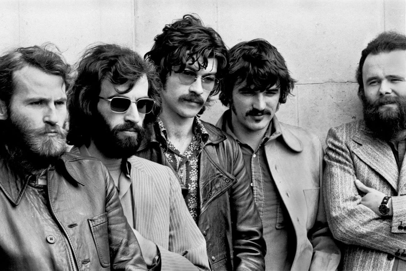 A black and white picture of Levon Helm, Richard Manuel, Robbie Robertson, Rick Danko and Garth Hudson of The Band posing against a wall.