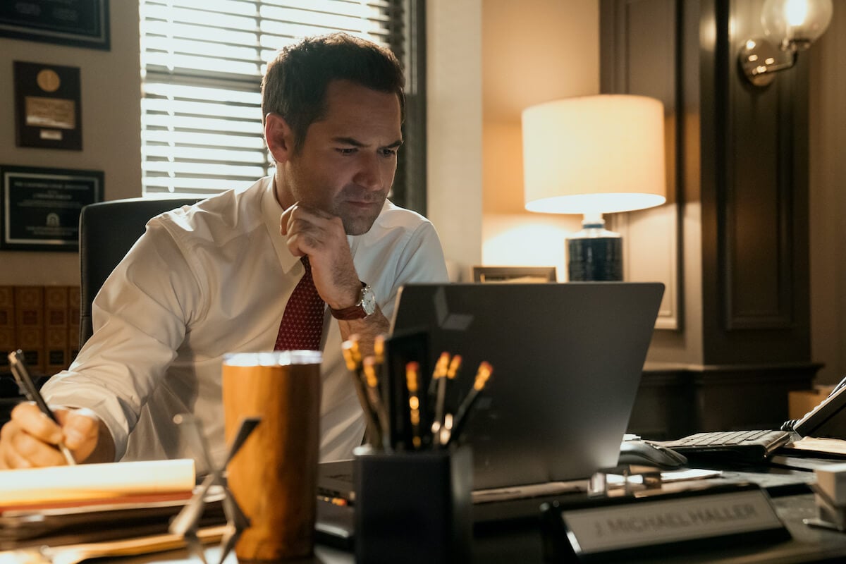 Manuel Garcia-Rulfo as Mickey Haller looking at a laptop screen in 'The Lincoln Lawyer' Season 2 on Netflix