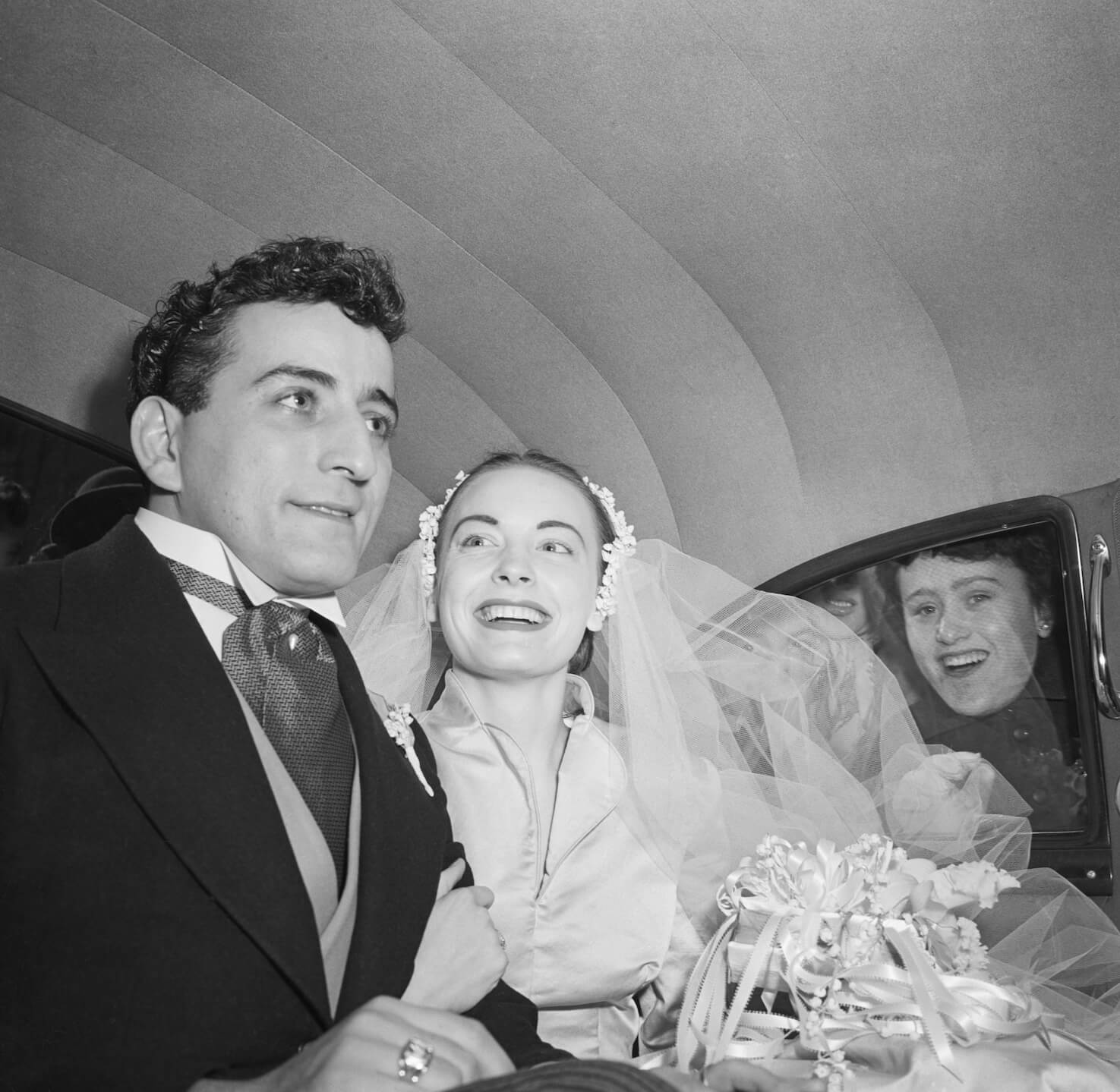 Tony Bennett and Patricia Beech smiling at each other in a car on their wedding day