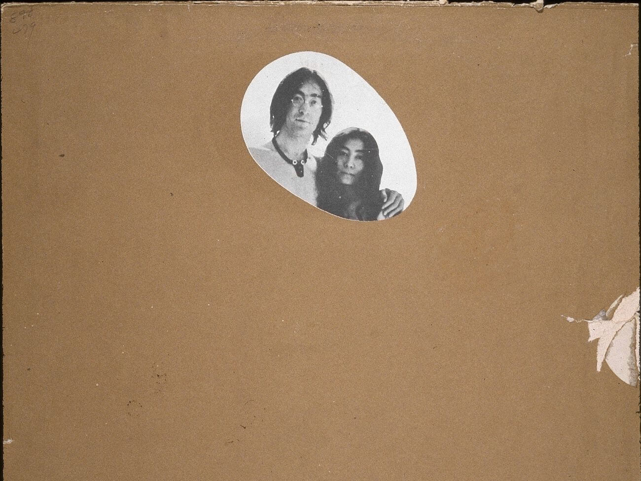 The album of 'Two Virgins' is mostly covered by brown paper except for an oval that reveals John Lennon and Yoko Ono's faces.