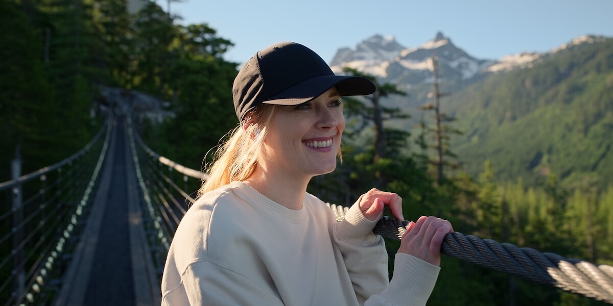 Mel standing on a bridge and wearing a baseball cap in 'Virgin River' Season 5
