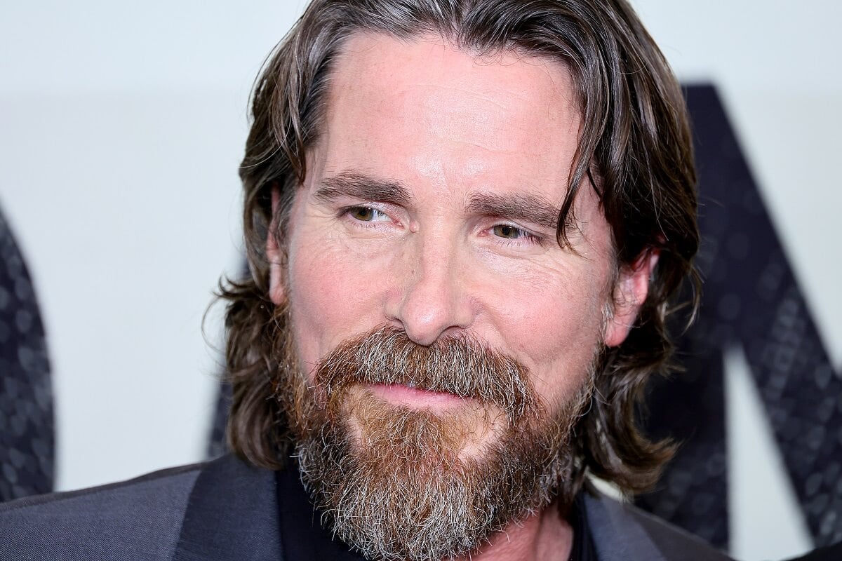 Christian Bale taking a picture in a suit at the premiere of the movie 'Amsterdam'.