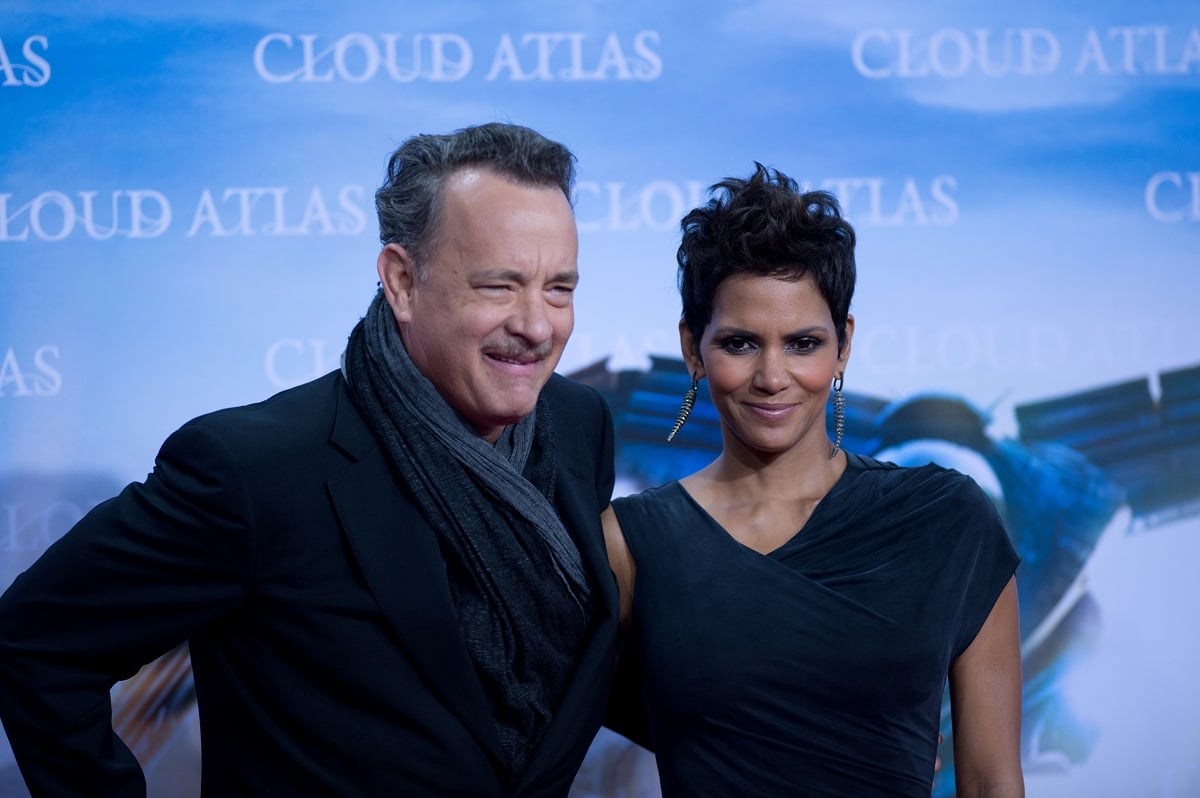 Halle Berry in a dress smiling next to Tom Hanks at the premiere of 'Cloud Atlas'.