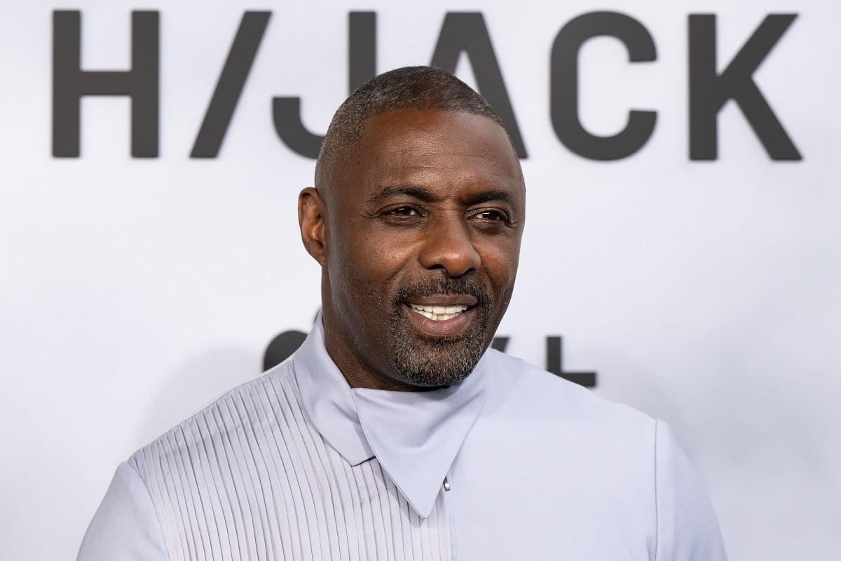 Idris Elba smiling in a white shirt in a picture at the 'Hijack' premiere.