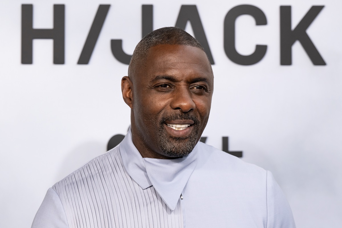 Idris Elba smiling in a white shirt in a picture at the 'Hijack' premiere.