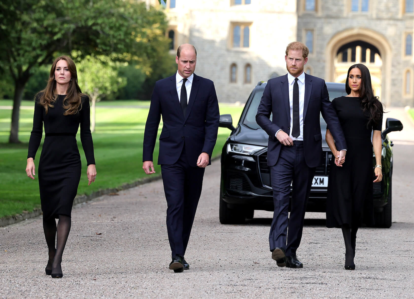 Kate Middleton, Prince William, Prince Harry, and Meghan Markle wearing black and walking