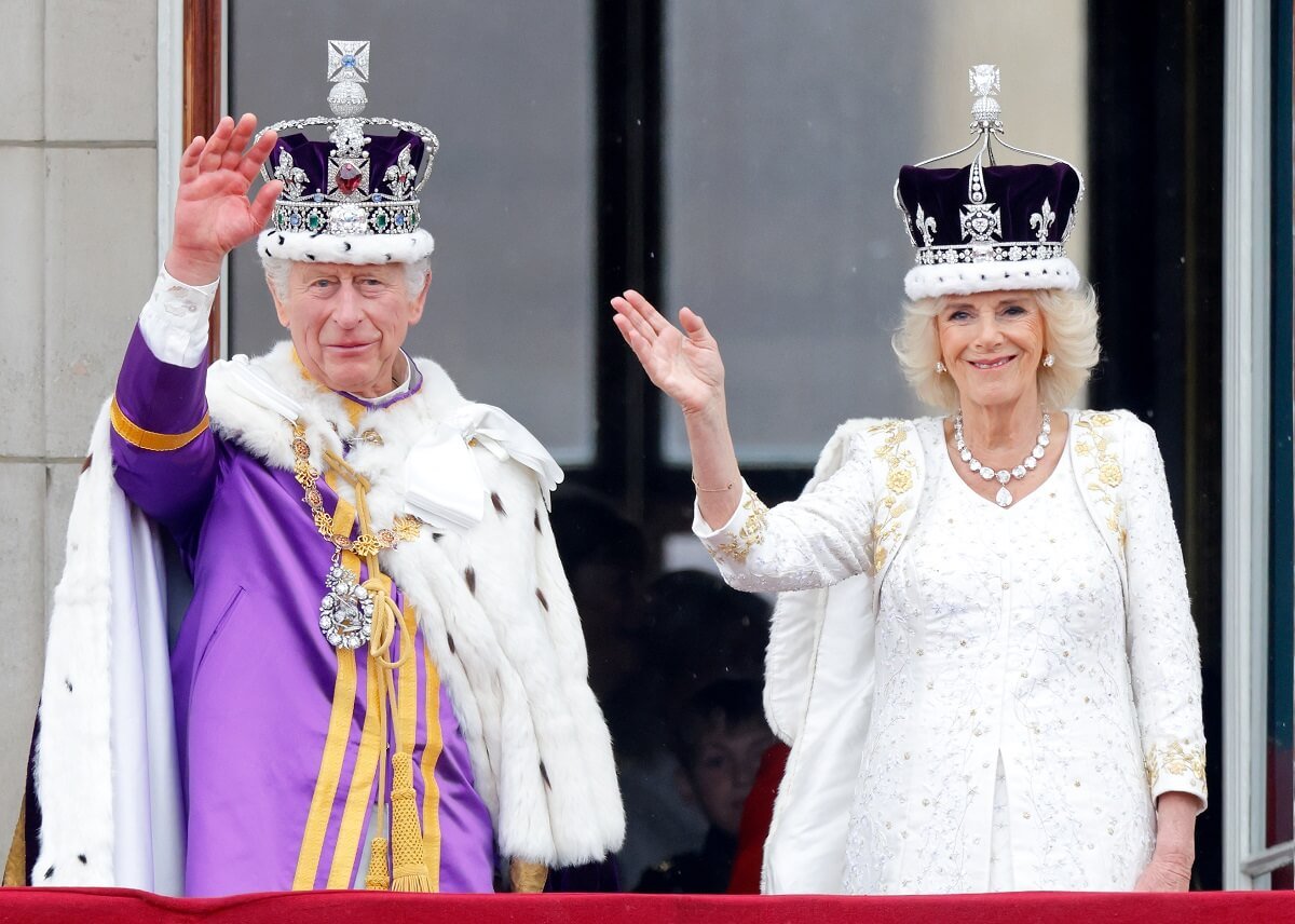 King Charles III and Queen Camilla waving from the balcony of Buckingham Palace following coronation ceremony