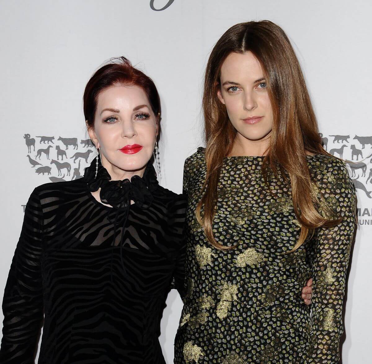 Lisa Marie Presley wears black and stands with her arm around Riley Keough, who wears green.