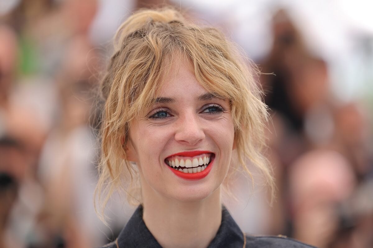 Maya Hawke smiling while taking a picture at the 'Asteroid City' photocall.