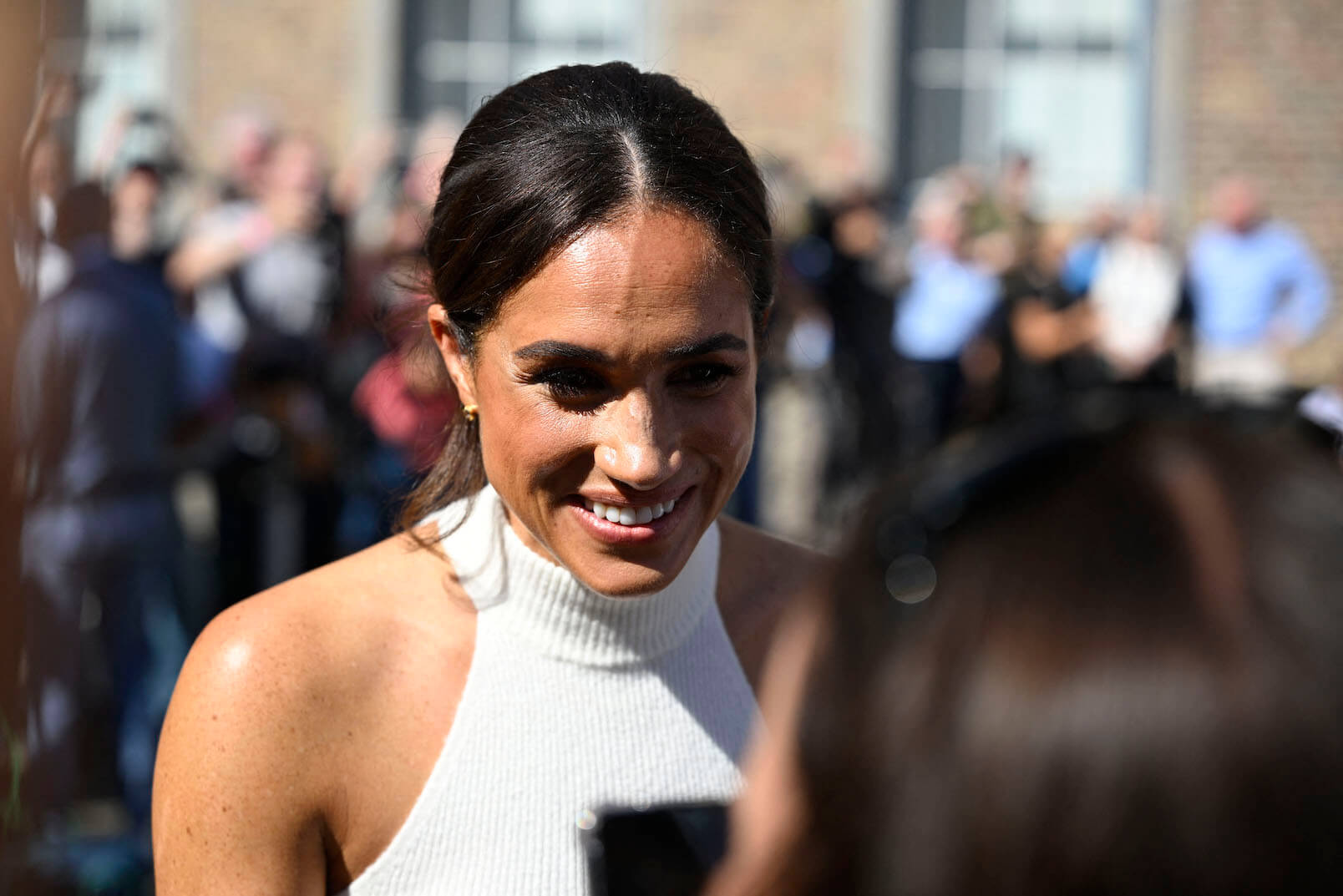 Meghan Markle smiling and talking with a wellwisher as she leaves the city hall in Duesseldorf, Germany