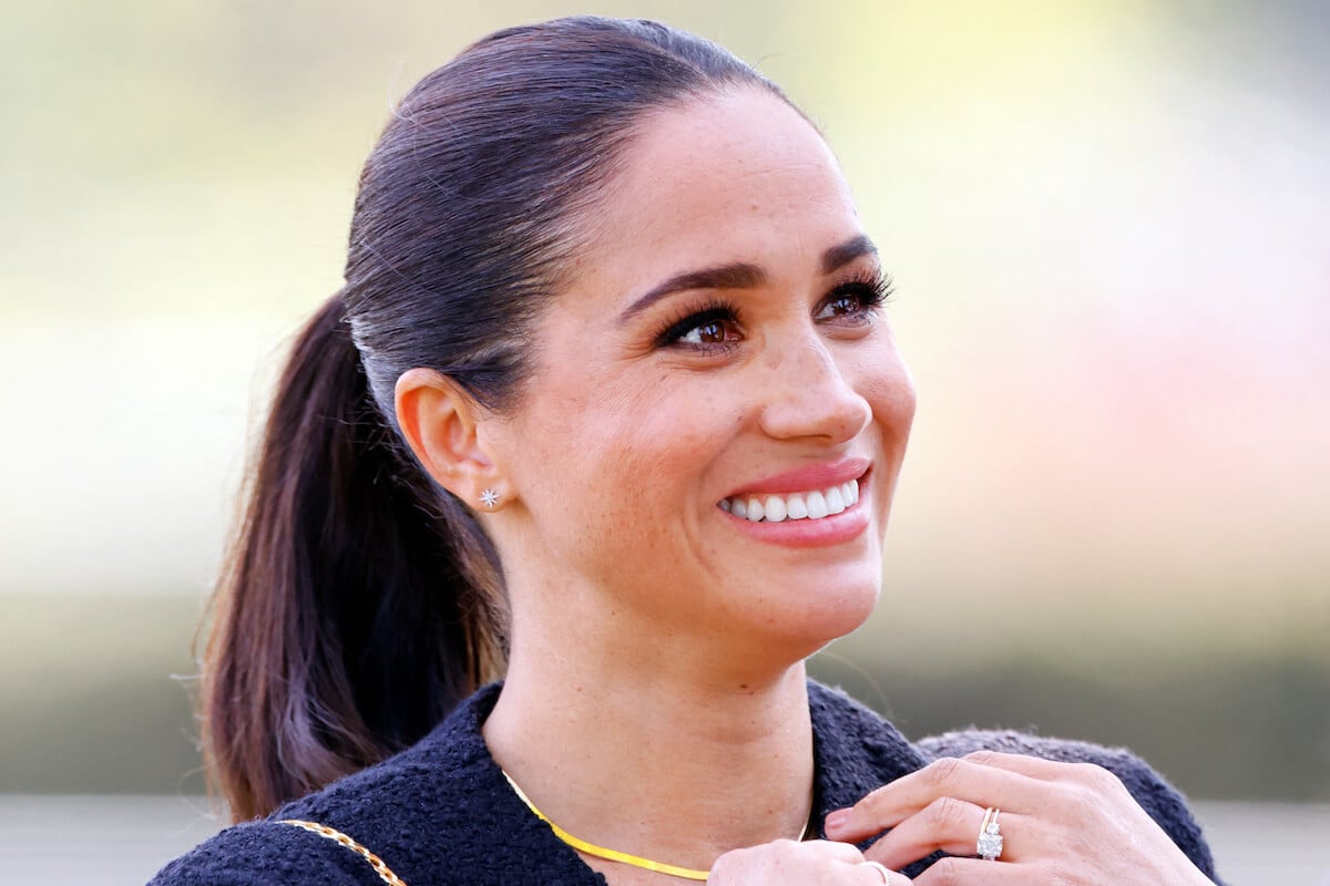 Meghan Markle, whom a commentator says not wearirng her engagement ring from Prince Harry may be for 'practicality,' smiles and looks on