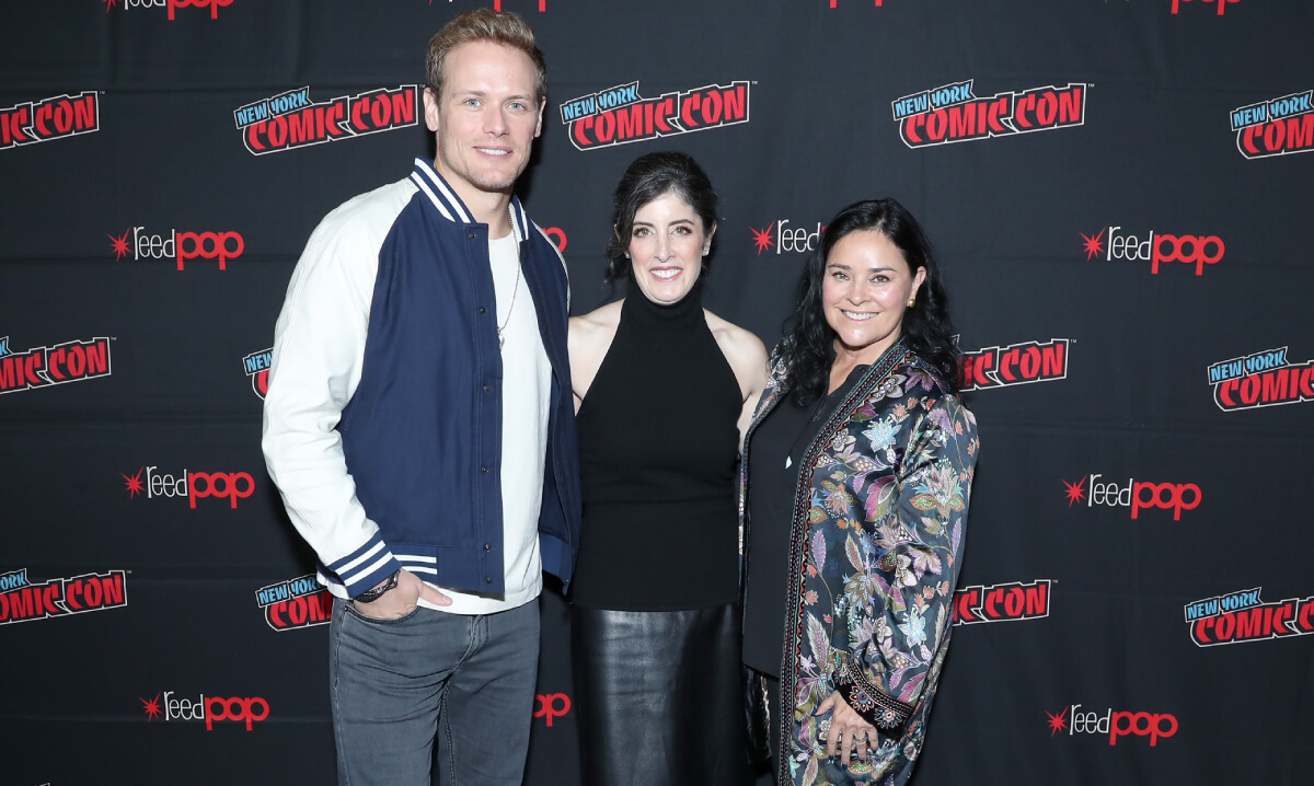 Sam Heughan, Maril Davis, and Diana Gabaldon pose for a photo together at the Outlander panel during Day 3 of New York Comic Con 2021