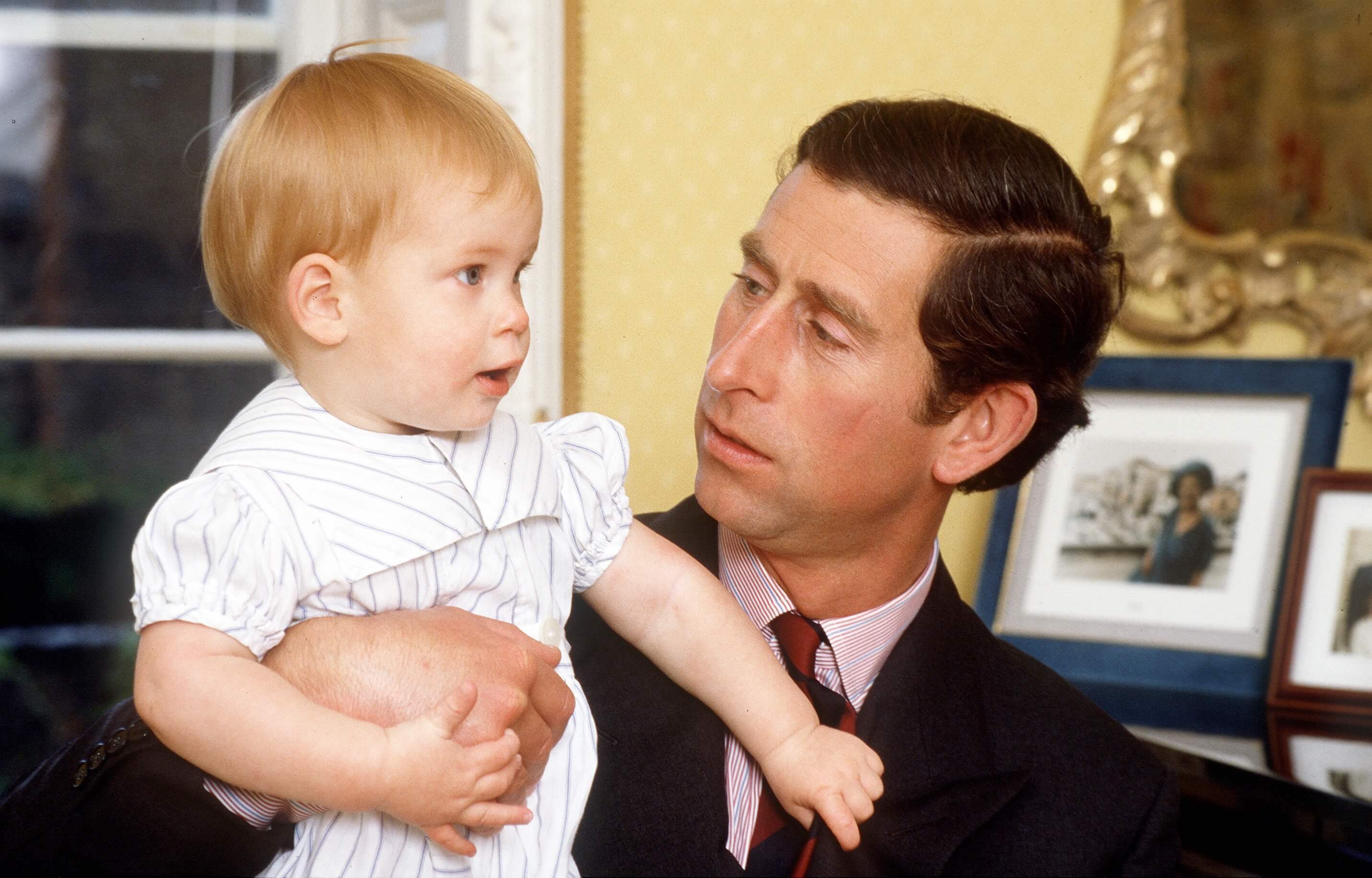 King Charles III holding baby Prince Harry