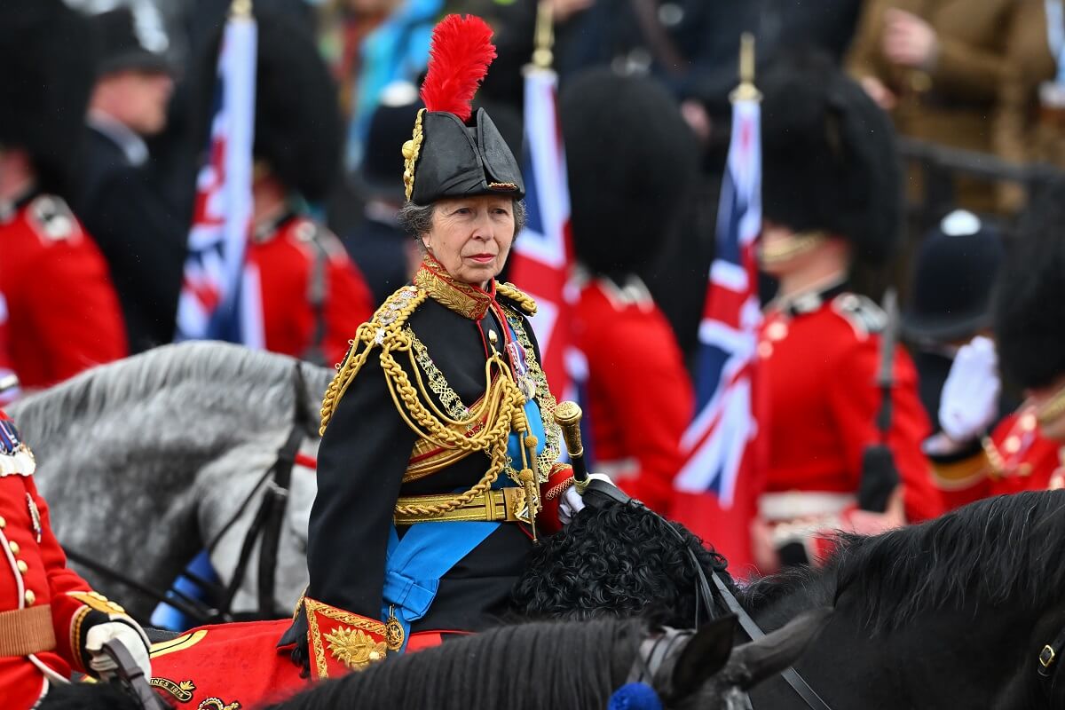 Princess Anne rides on horseback behind the gold state coach carrying King Charles III during the coronation