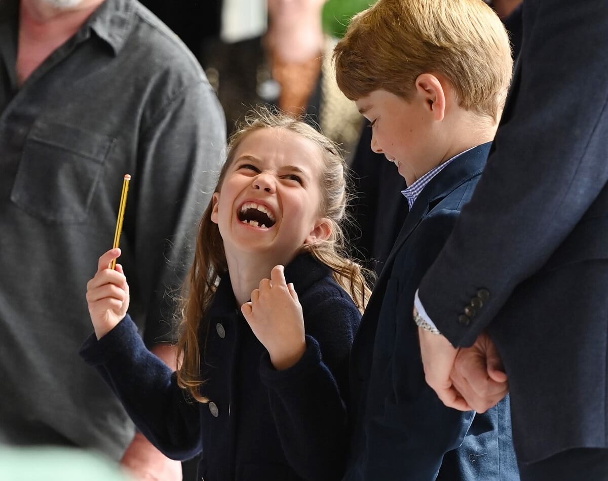 Princess Charlotte laughs as she conducts a band next to her brother Prince George at Cardiff Castle