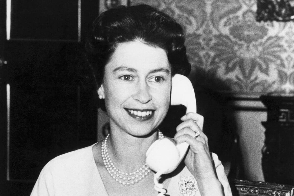 Queen Elizabeth II, who had a cell phone, holds a phone receiver to her ear