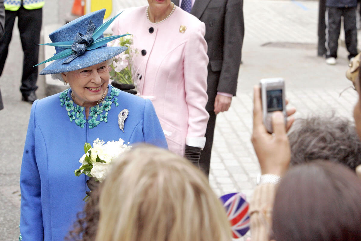 Queen Elizabeth II, who had her own cell phone, smiles as people take photos of her on their cell phones