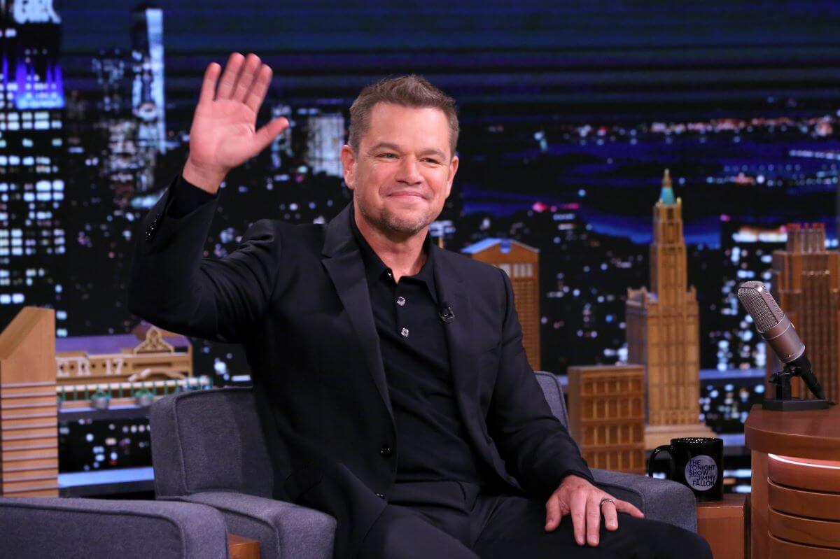 Matt Damon waves while sitting in an armchair on the set of 'The Tonight Show.'