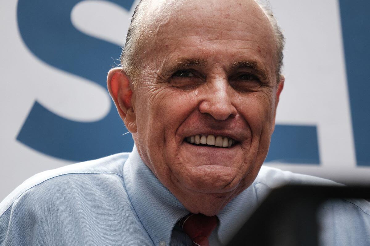 Rudy Giuliani wears a blue collared shirt and a tie.