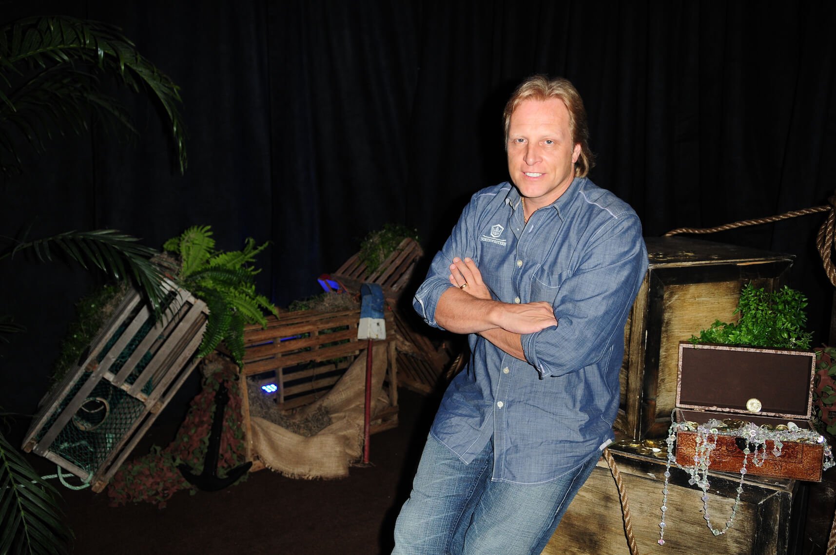 Sig Hansen from 'Deadliest Catch' leaning against a chest with his arms crossed