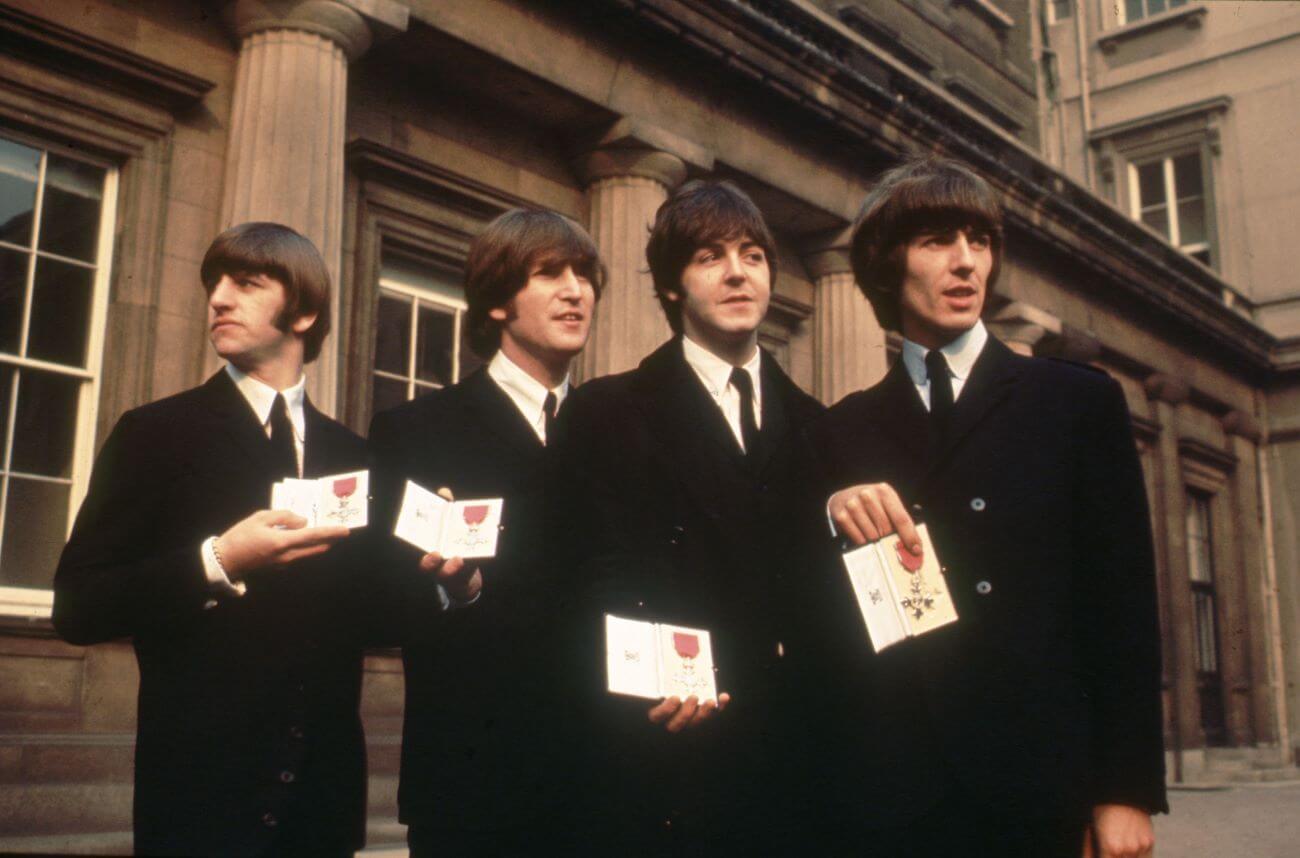 The Beatles hold their MBEs outside of Buckingham Palace.